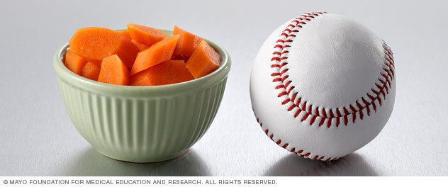 Half a cup of cooked carrots next to a baseball.