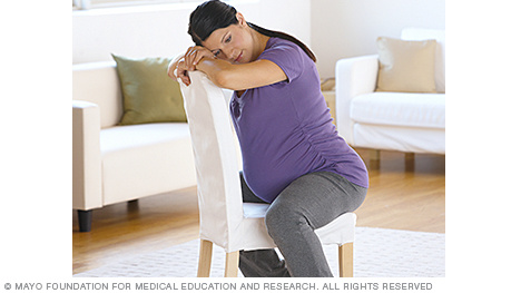 A person in labor leaning forward against a chair